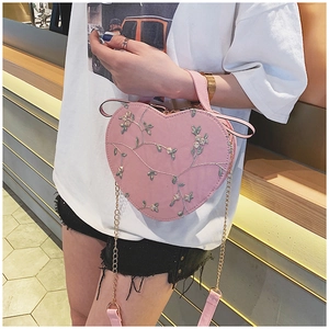 Detailed view of pink heart-shaped bag with floral embroidery and gold chain strap
