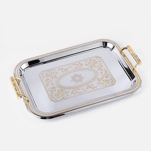 Macro detail of rectangle stainless steel tray with golden floral engraving and handles