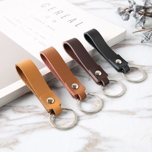 Close-up of four leather loop keychains in various colors on marble surface