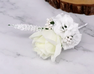 Detail of a handmade white silk rose wedding boutonniere on a white marble surface