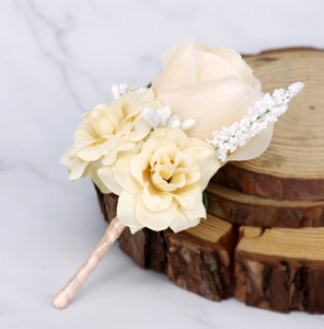 Detail of champagne wedding boutonniere with silk ribbon on wooden tree slice background