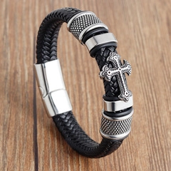 Detail of woven black leather bracelet with silver cross pendant on wood surface