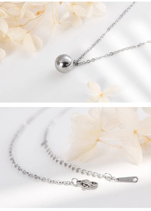 Close-up of a minimalist silver stainless steel necklace featuring a round bead pendant