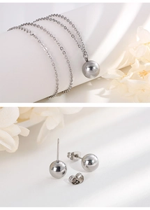Detail view of silver round ball pendant necklace and stud earrings set on a clean background