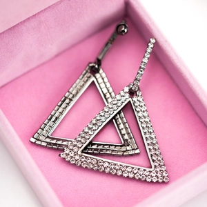 Pendientes geométricos de triángulo con diamantes de imitación en un joyero de terciopelo