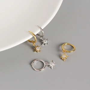 Macro shot of silver and gold eight-pointed star hoop earrings with sparkling zircon stones