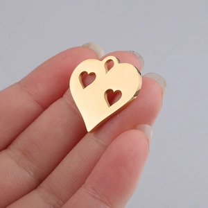 Polished gold hollow heart charm pendant in stainless steel held between fingers