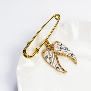 Detail of angel wing brooch with blue evil eye on white ceramic plate