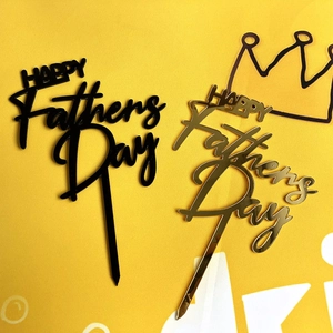 Detail of black and mirror gold acrylic Happy Father's Day cake toppers on yellow background