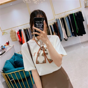 White short-sleeve T-shirt with brown patterned neck scarf and deep brown skirt