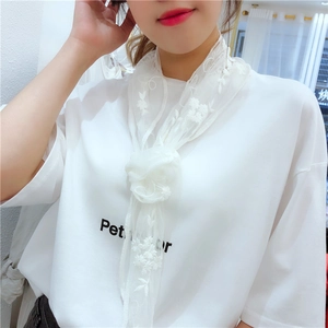 Close-up of white lace scarf with floral embroidery and wavy edges on woman's neck