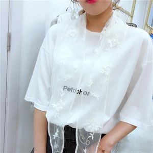 Detail of white lace scarf with floral embroidery layered over a printed t-shirt
