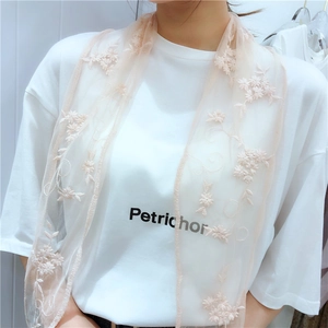 Close-up of apricot pink lace scarf with delicate 3D floral embroidery and wavy edges