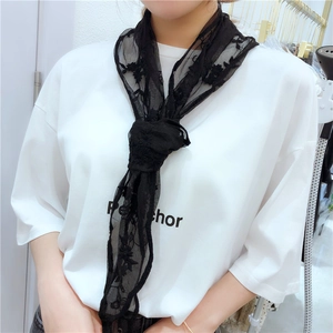 Detail of black lace scarf with floral embroidery tied around a model's neck