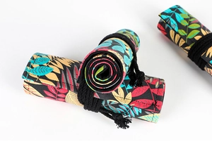 Detail of rolled canvas pencil wrap with colorful leaf pattern and black tie closure