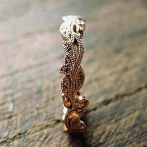 Macro detail van roségouden bladring met witte steentjes op donker hout