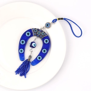 Detailed view of blue evil eye horseshoe pendant with silver metal and beaded tassels