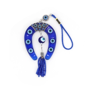 Detail of blue evil eye horseshoe charm with hanging resin bead and tassel decoration