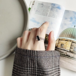 Detail of layered 925 silver ring with black rectangular stone on a hand with minimal props