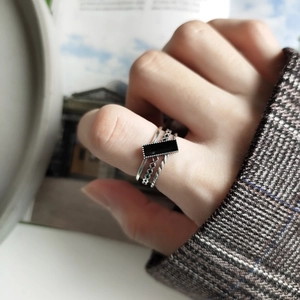 Close-up of stacked S925 silver rings with a black rectangular gemstone on a model's hand