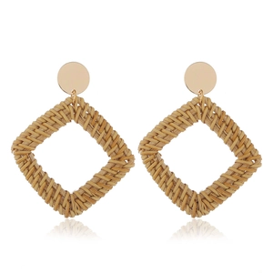 Détail de boucles d'oreilles géométriques en rotin tressé avec clou en métal doré