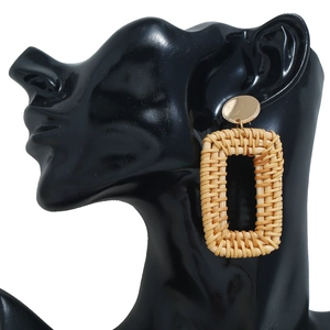 Détail de boucles d'oreilles rectangulaires en rotin tressé à la main sur modèle