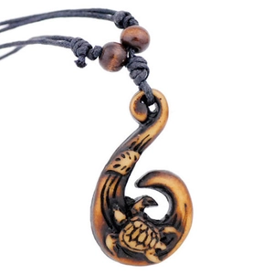 Close-up of Maori fish hook pendant with turtle carving on black braided cord