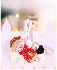 Close-up of a plush snowman ornament with plaid scarf and hat hanging on a white fence