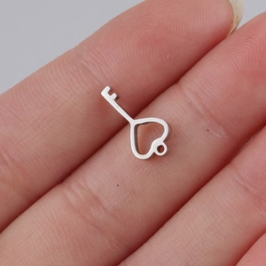 Macro view of a tiny mirror-polished heart key pendant held between fingers