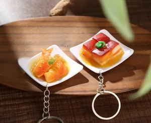 Detail of realistic PVC braised meat and fish food models with silver metal keychains