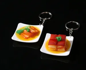 Detailed close-up of realistic braised pork food model keychain on mini plate