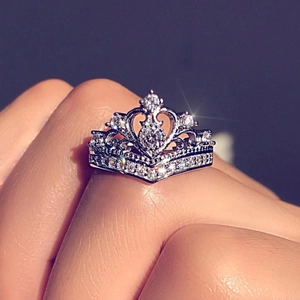 Macro shot of a crown-shaped silver ring with zircon stones on a person's finger