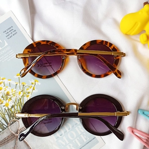 Close-up of retro round kids sunglasses with tortoise and black frames and UV400 lenses
