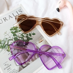 Detail of heart-shaped sunglasses with transparent frames in purple and tea colors