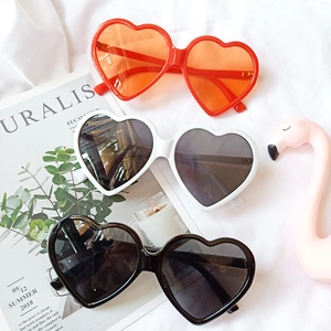 Detailed view of red, white, and black heart-shaped sunglasses in a trendy summer setting