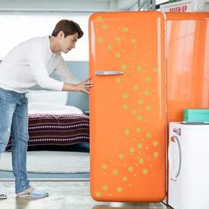 Luminous green snowflake stickers on a vintage orange fridge in a bright modern home
