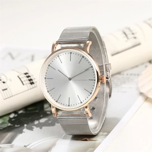 Modern rose gold watch with silver mesh band and radial sunray dial on sheet music background