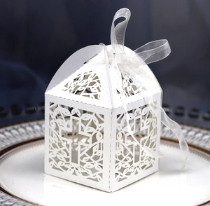 Macro detail of white hollow laser-cut wedding favor box with cross and ribbon