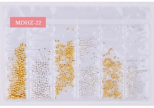 Macro detail of mixed gold and silver nail art micro beads in a 6-compartment set