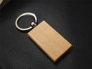 Macro shot of rectangular beech wood keychain showing natural wood grain on black leather