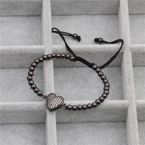 Détail du bracelet cœur en métal gris avec zircon micro-pavé sur cordon tressé noir