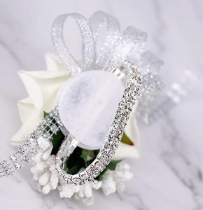 Macro shot of double-row crystal bridal wristlet with white faux flowers and silver ribbons