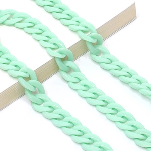 Close-up of mint green acrylic chain links on a white book for fashion styling