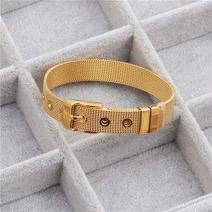Macro detail of golden mesh strap bracelet with adjustable buckle on gray velvet