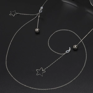 Silberne Brillenkette aus Metall mit Sternanhängern und Perlen auf schwarzem Grund