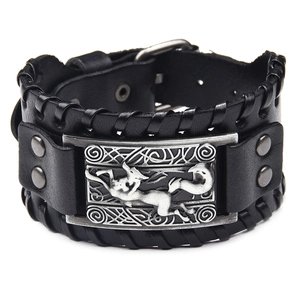 Macro detail of wide black leather bracelet with embossed fox metal plate and woven texture