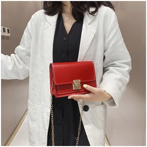 Détail du sac bandoulière rouge avec coutures blanches et fermoir doré en cuir