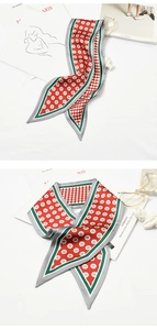 Close-up of a red and grey polka dot silk scarf with geometric stripes on a white surface