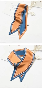 Flat lay of an elegant striped orange and blue silk scarf with artistic props