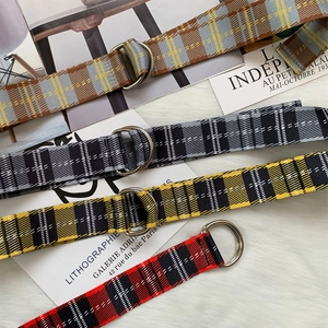Detail of four checkered nylon canvas belts with metal double D-ring buckles on white fur